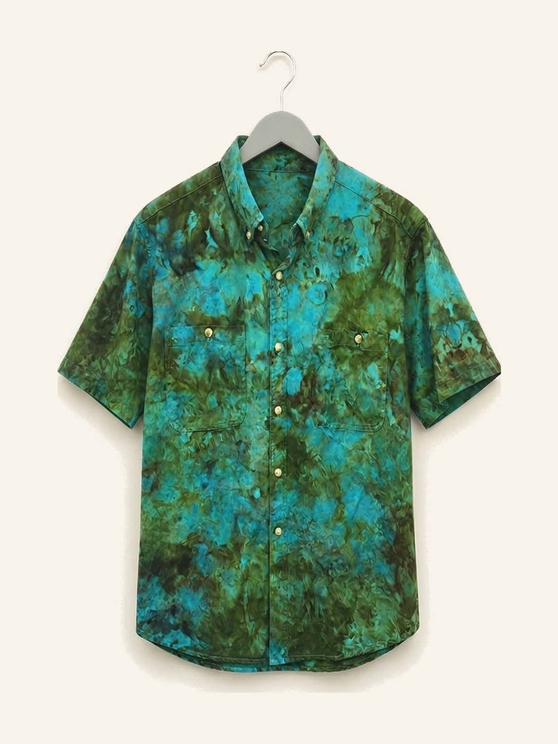 Hand ice-dyed cotton shirt in green and teal on a wooden hanger