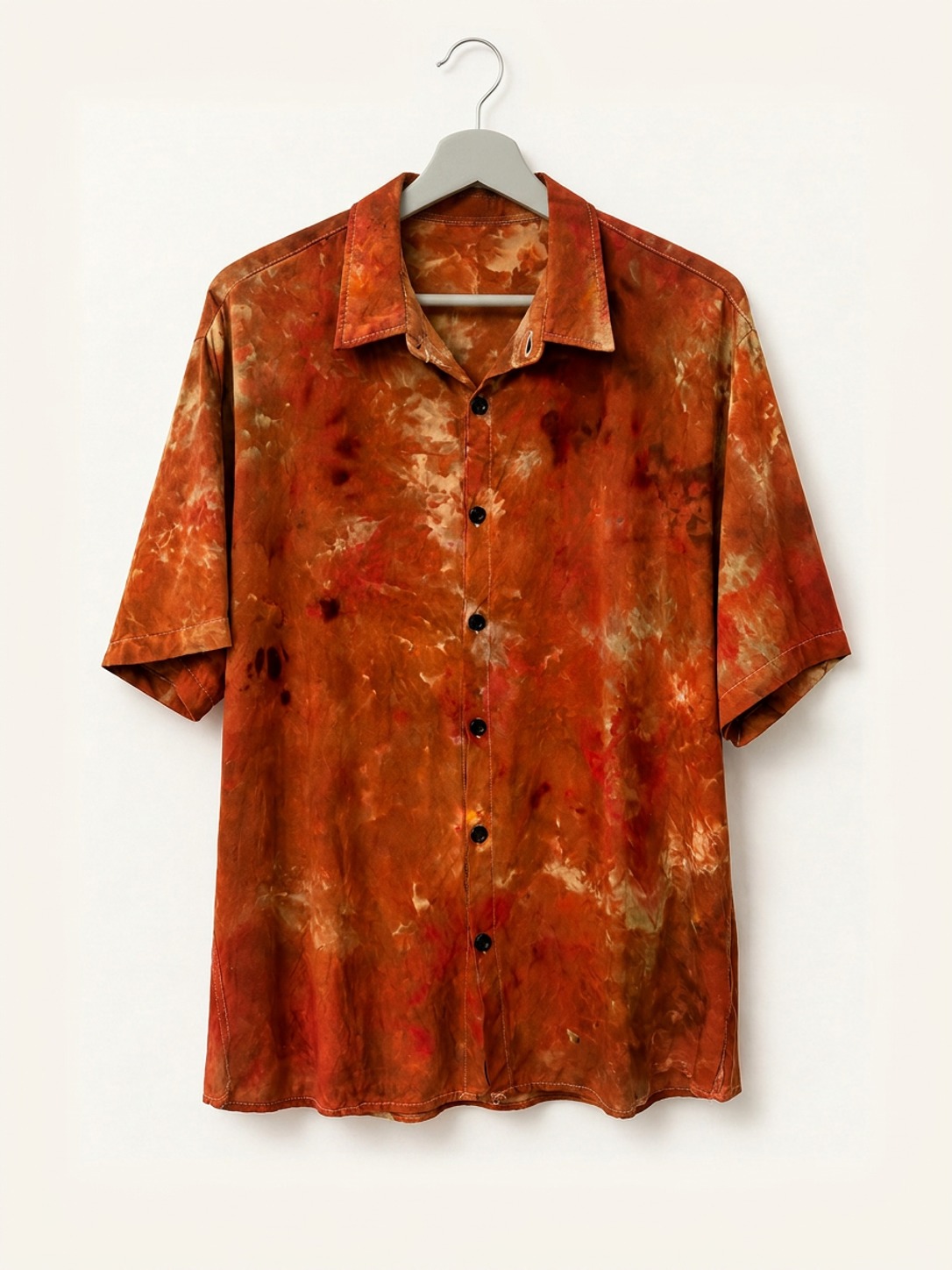 Hand ice-dyed bamboo collar shirt in rust, sand and orange on a wooden hanger